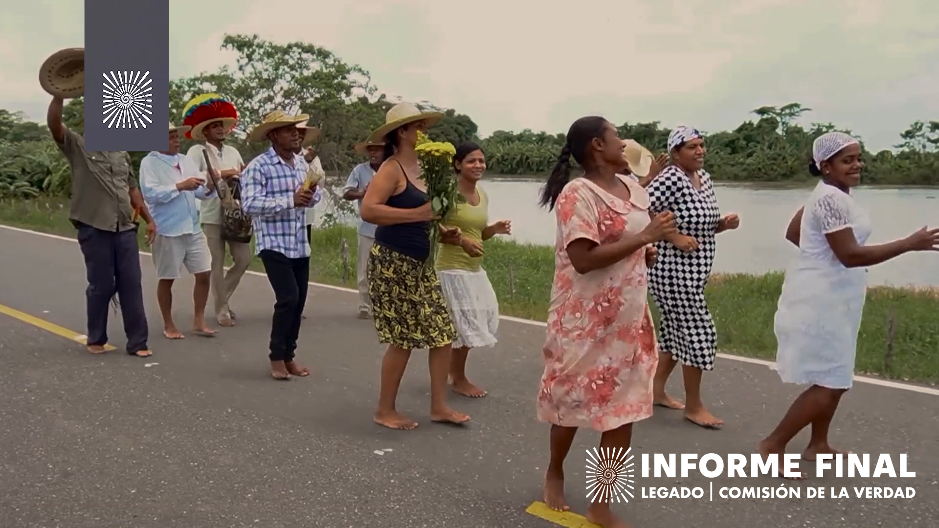 Un grupo de doce hombres y mujeres avanzan descalzos cantando y bailando contentos por una carretera