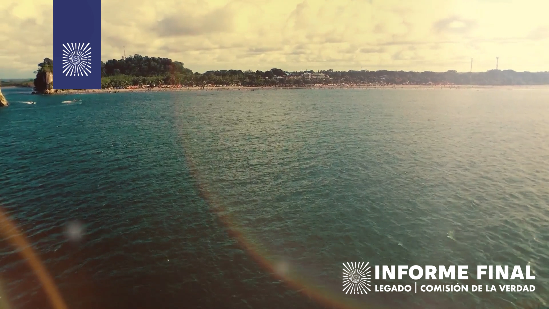 Playa con sombrillas observada desde mar adentro, el sol genera arcoiris en lente.