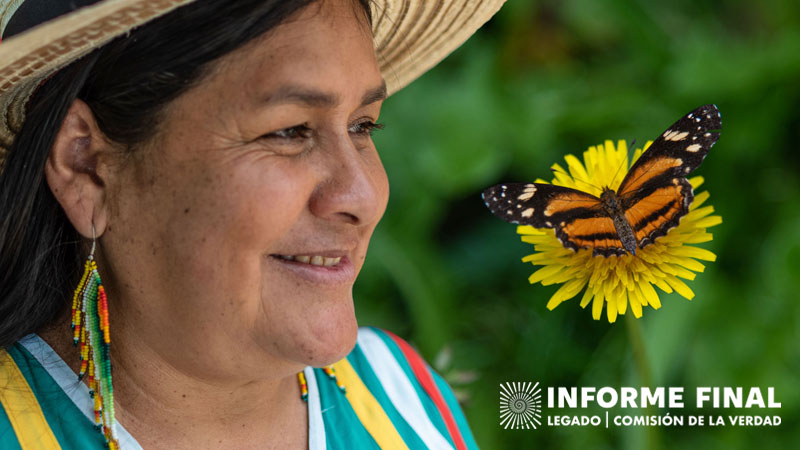 Mujer con sombrero de perfil sonrie, frente a ella una flor diente de león y posada en ella una mariposa