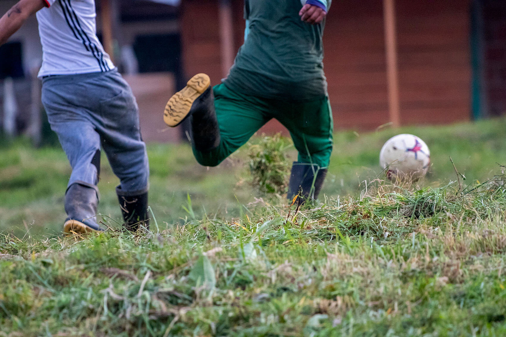 Sobre pasto seco y recién cortado, dos firmantes de la paz juegan fútbol con botas pantaneras.