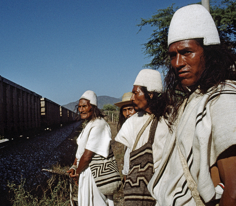 Mamos Arhuacos esperan paso del tren de carga de Carbón, Cienaga- Magdalena .«Un grupo de mamos arhuacos recorrieron los sitios sagrados que marcan la Línea Negra, la frontera del territorio ancestral de la Sierra Nevada de Santa Marta, para realizar trabajos espirituales. Es la forma tradicional de sanar el daño espiritual causado por grupos armados que penetran el territorio indígena». 