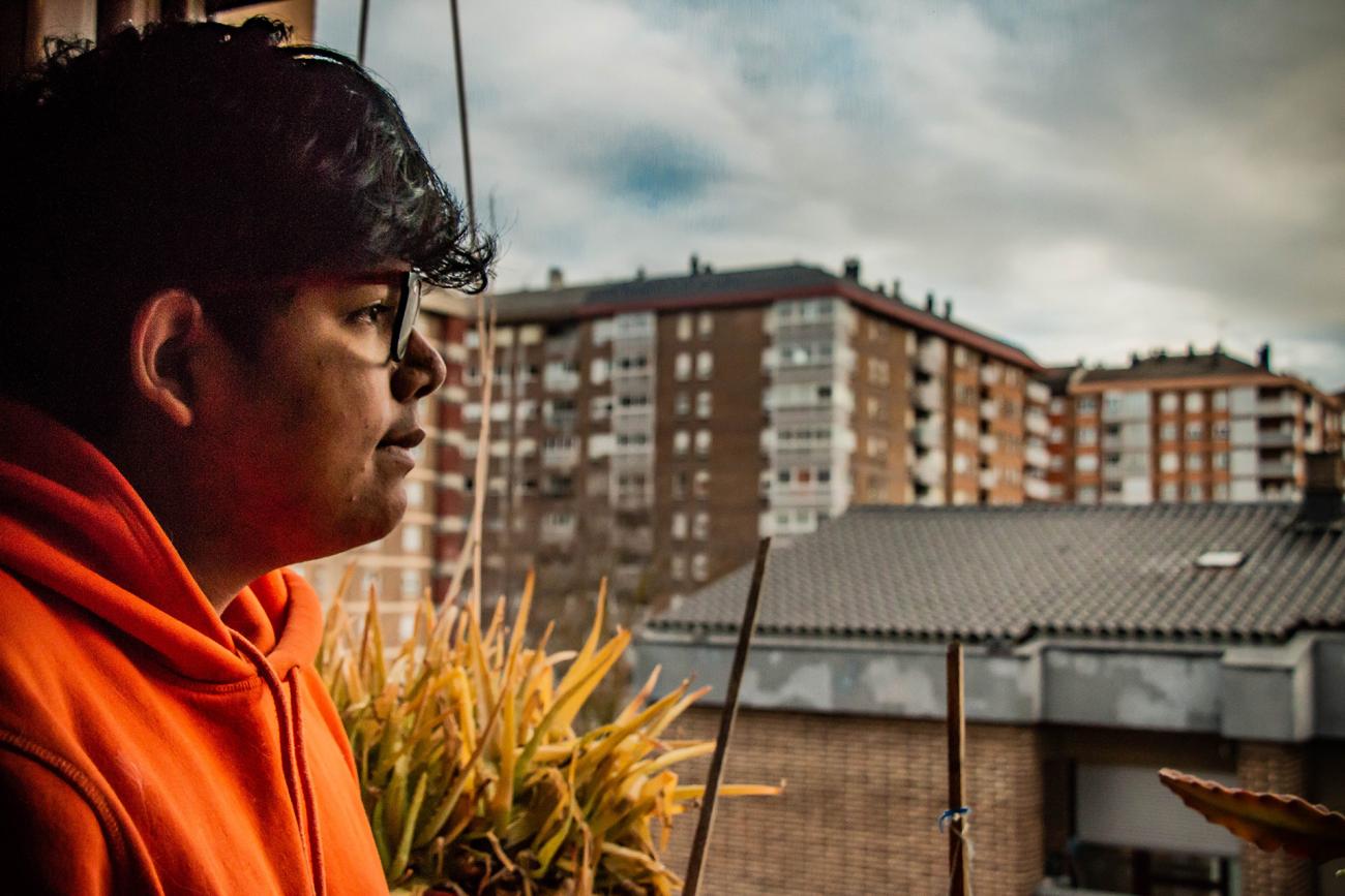 perfil de joven con gafas mirando al horizonte, al fondo edificios