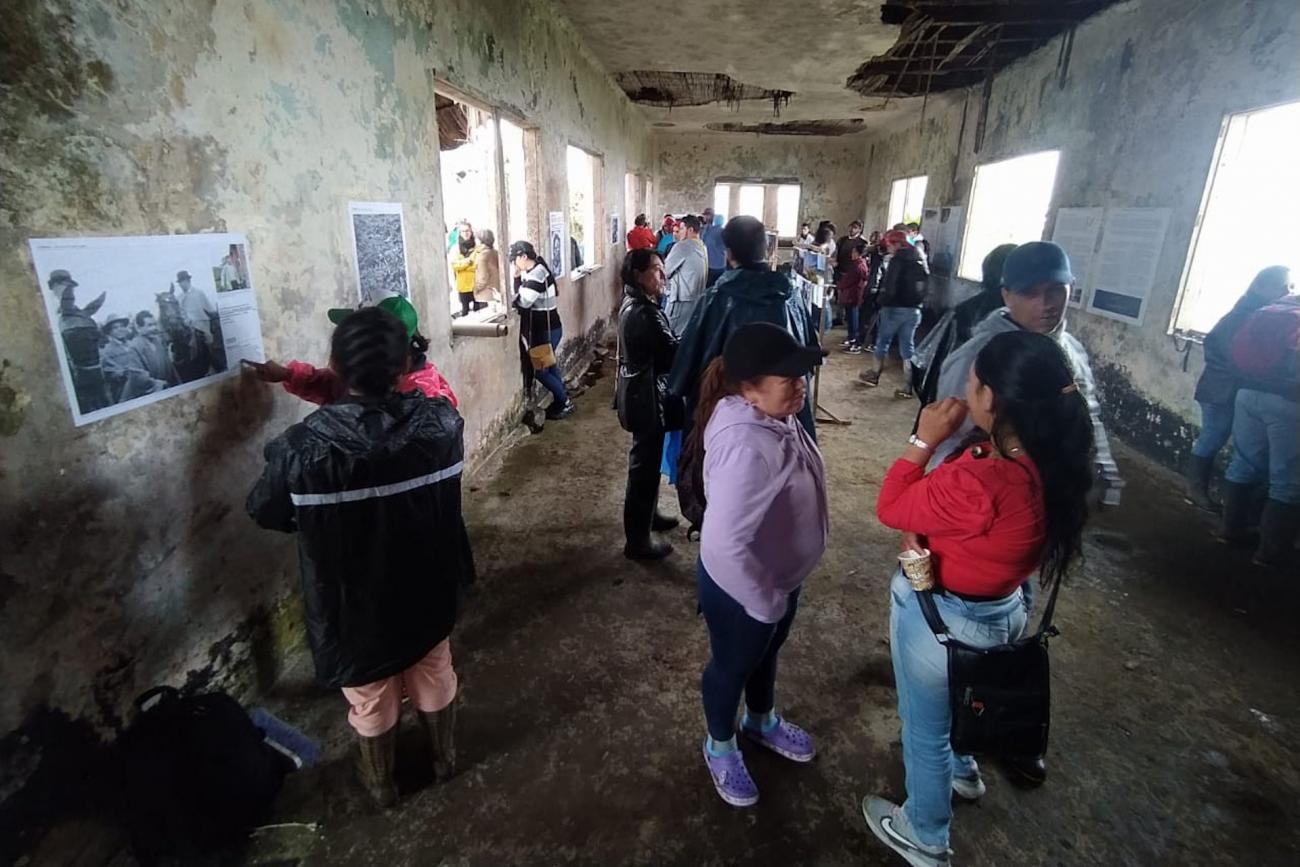 Personas observan afiches pegados a los muros en un salón sin ventanas de una edificación abandonada
