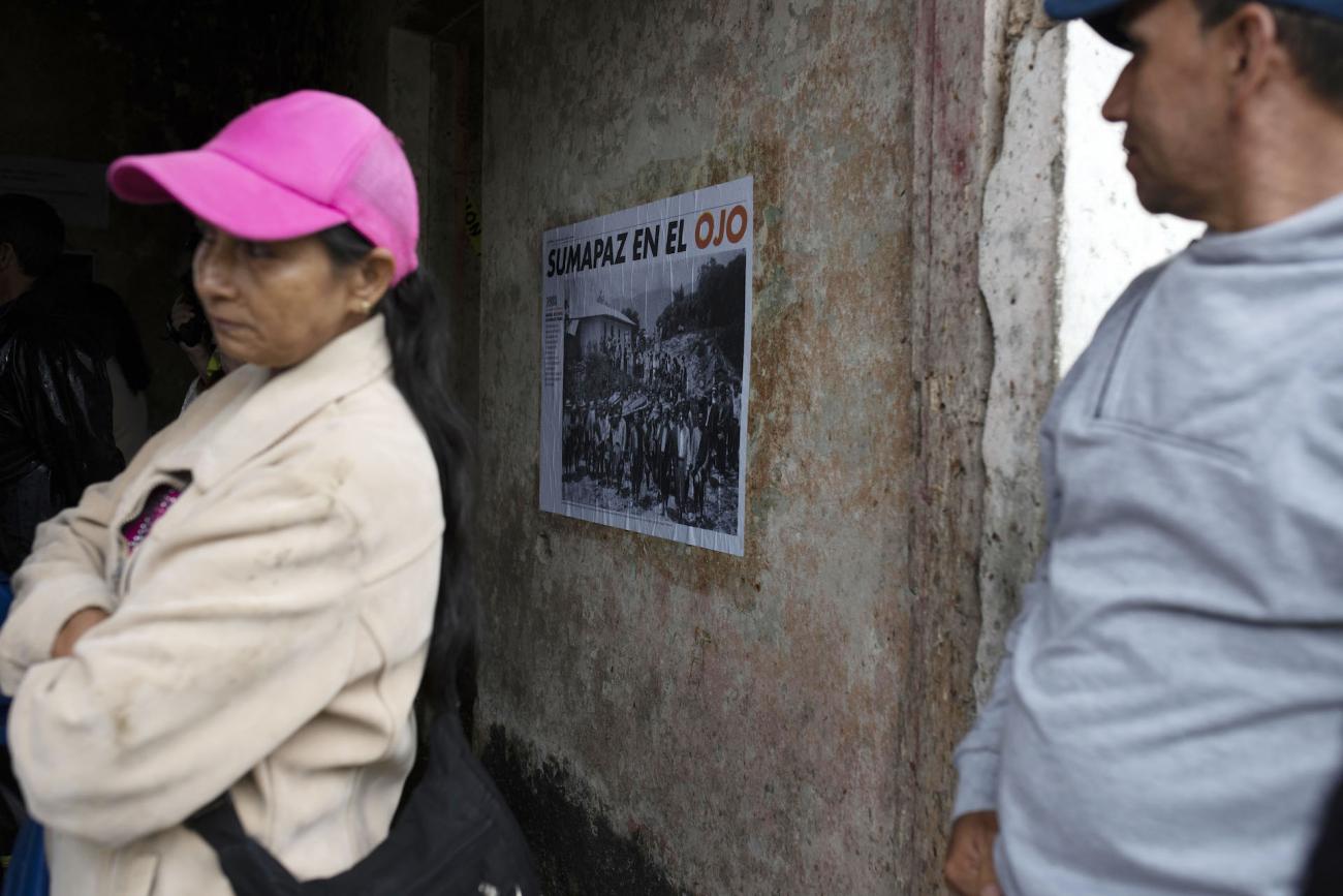 2 Personas al lado de un afiche pegado al muro de una edificación abandonada. Texto: Sumapaz en el ojo