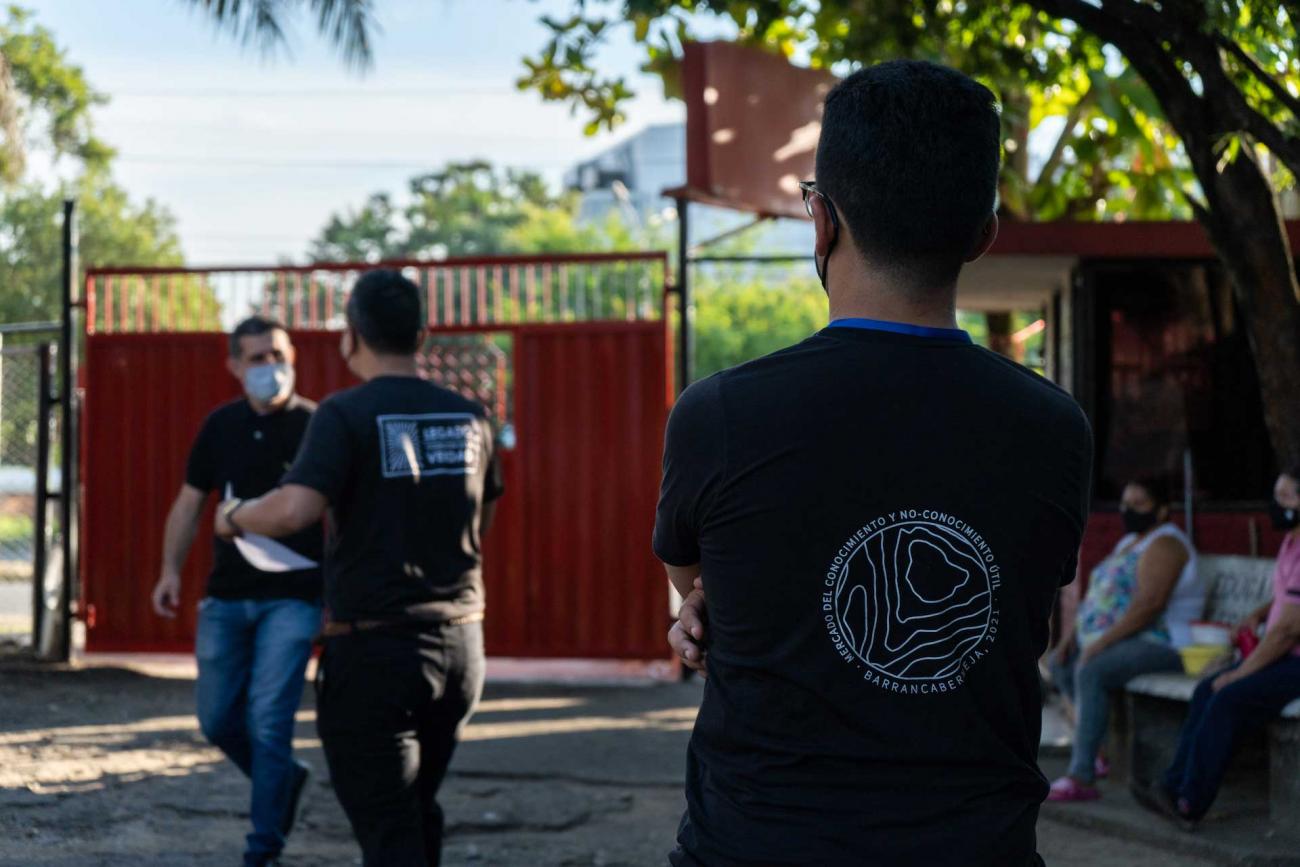 Entrada del evento. Puerta de acceso vehicular. Personas conversando