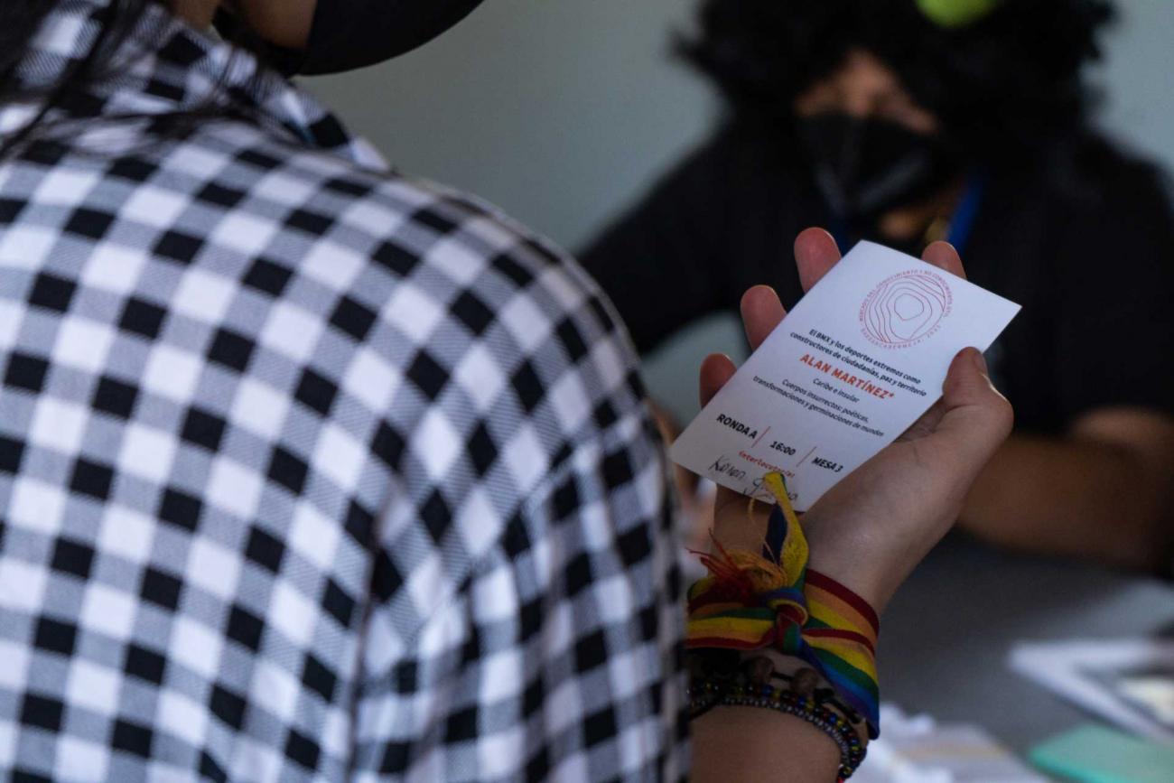 Persona sosteniendo en su mano la escarapela de entrada al evento