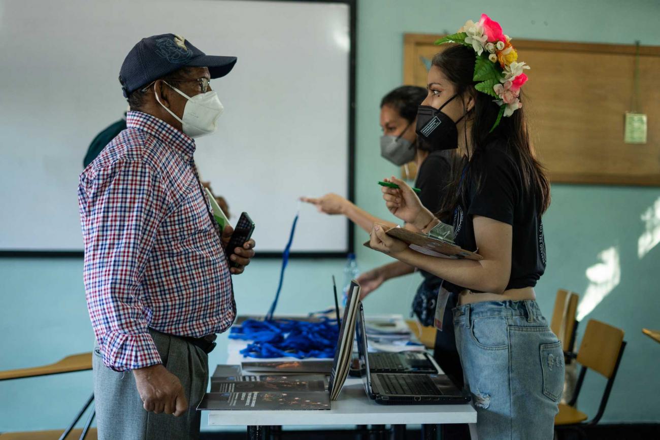 Mujer con arreglo de flores en la cabeza tomando datos de hombre asistente al evento