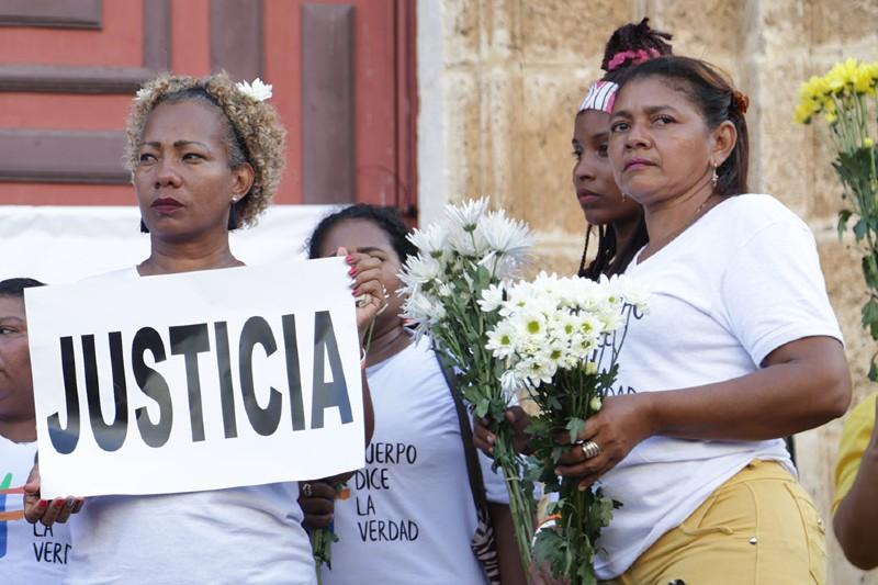 Mujeres sostienen un cartel con la palabra justicia