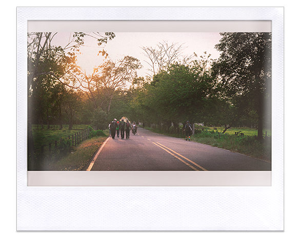 Instantánea. Personas caminando por una carretera en el atardecer