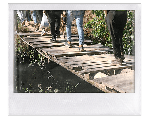 Instantánea. Personas caminando sobre un puente de madera al que le faltan tablones