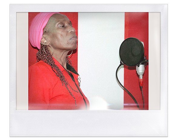  Instantánea. Mujer afro con trenzas y turbante rojo frente a un micrófono