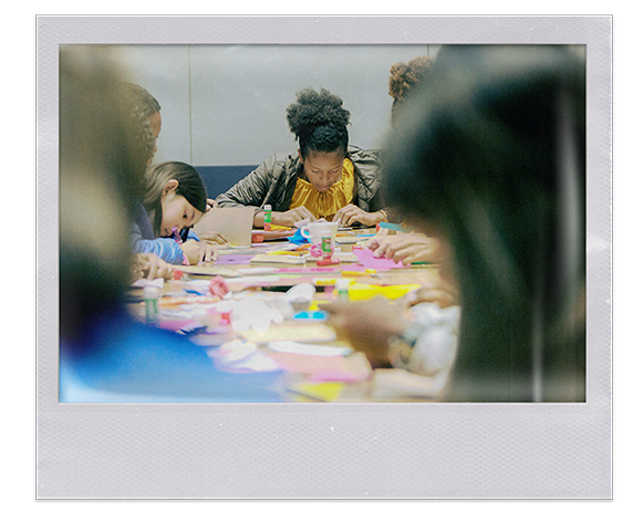 Instantánea. grupo de niños, niñas y adolecentes, haciendo manualidades sobre una mesa con elementos de colores