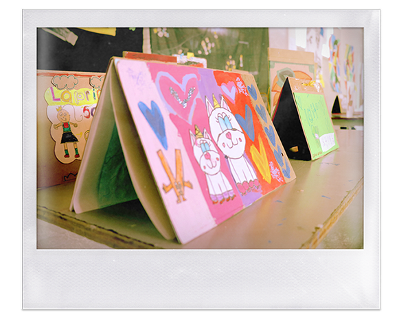 Instantánea. Dibujos puestos como calendario triangular, pintados con gatos unicornio y corazones, otro de niña sonriente