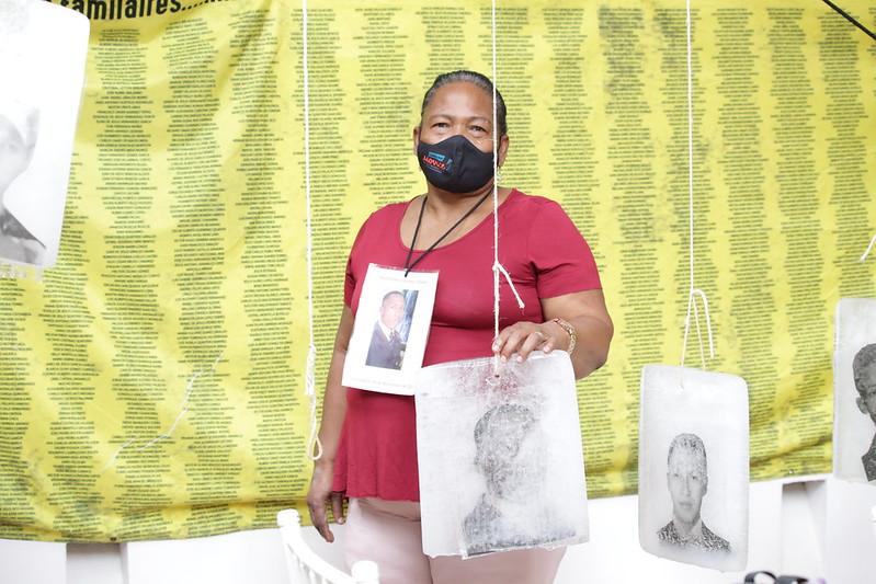 Mujer junto a fotografía de los jóvenes asesinados por paramilitares