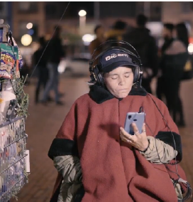 Mujer vendedora en la calle, sentada y concentrada viendo un video por medio de un celular